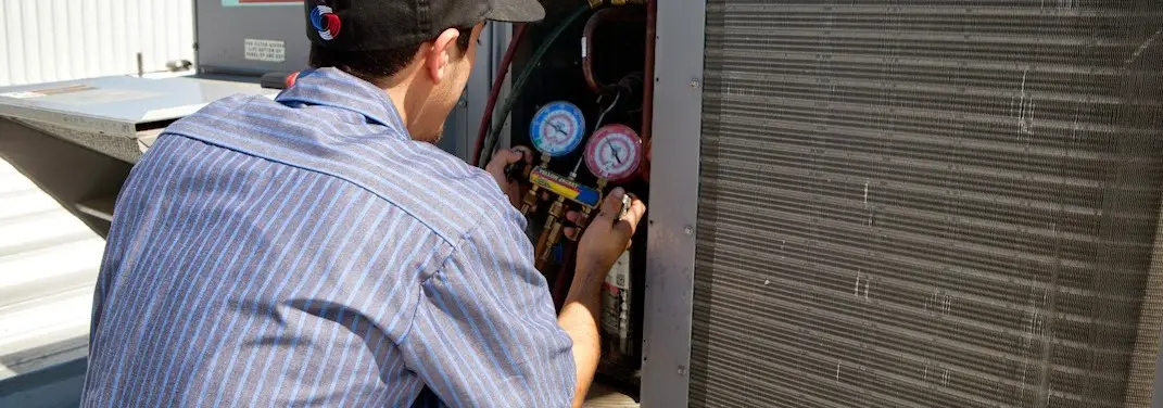 HVAC technician servicing a condenser unit in Southgate